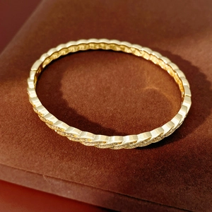 Macro detail of twisted gold plated bracelet with pavé cubic zirconia on velvet stand