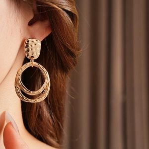 Macro detail of gold geometric hammer-textured earrings on model's ear