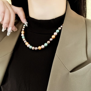 Détail de perles rondes colorées aux tons vert, rose et champagne sur un bracelet élastique