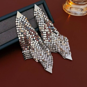 Detailed view of silver mesh fringe earrings with metallic scales in a jewelry box