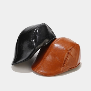 Detailed view of black and tan vintage PU leather newsboy caps with polished texture