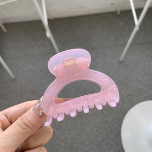 Pink translucent butterfly hair claw clip with golden spring held in hand