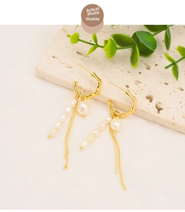 Detailed shot of bamboo-style gold hoop earrings with white pearls and long metal tassels