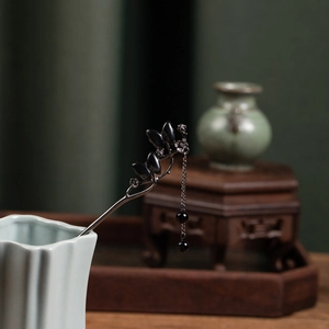 Detail of elegant Chinese style hair pin with black flower, tassel and pearl elements