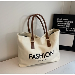 Detailaufnahme der cremefarbenen Canvas-Tote-Bag mit braunen Lederriemen und Paris-Logo