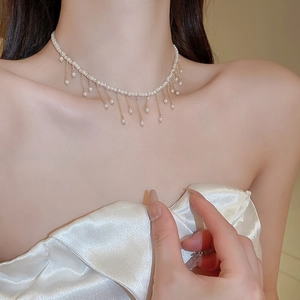 Detailed view of pearl choker necklace with gold fringe tassels on model's neckline