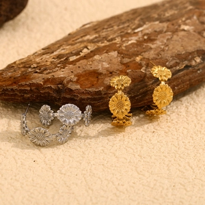 Détails macro de boucles d'oreilles marguerites dorées et argentées sur décor en bois