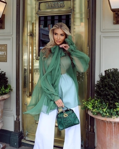 Detail of dark green chiffon blouse featuring elegant pussy-bow neck and ruffled cuffs