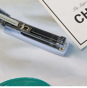 Detail of light blue stapler with metal loading slot and spring mechanism visible