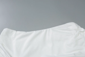 Detail of the elegant white asymmetric neckline on the slim-fit stretch knit dress