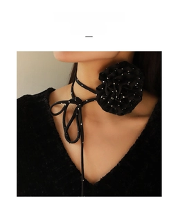 Detail of black chiffon choker necklace with white polka dots and large 3D rose flower