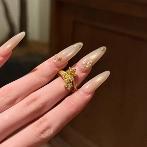 Elegant gold plated star ring with zircon stones shown on a finger in warm lighting