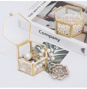 Detail of hexagonal glass jewelry box with gold metal frame and pearl necklace display