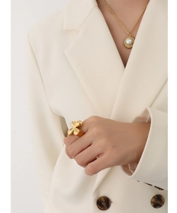 Detailed close-up of a minimalist gold cross ring and a vintage pearl pendant necklace