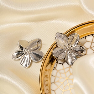 Macro shot of silver flower earrings on a silk background showing metal textures