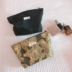 Detailed embroidery of floral makeup bags on white linen with high-end skincare products
