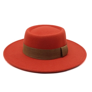 Close-up of orange wool felt flat top boater hat with a brown wide decorative band