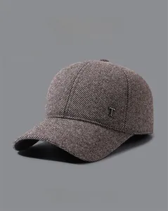 Detail of a brown tweed winter baseball cap for men featuring a metallic T-logo decoration