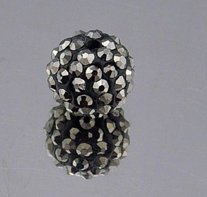 Macro detail of 8mm black Shamballa clay bead with sparkling silver pavé crystals