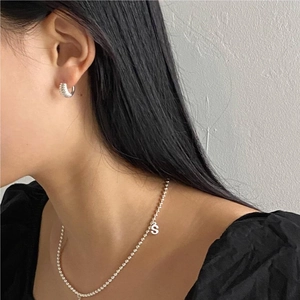 Detail of 925 sterling silver S-pendant beaded necklace and textured hoop earrings on model