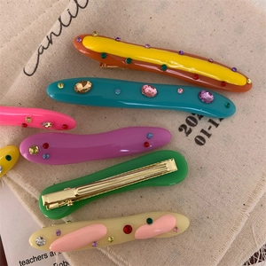 Detailed view of colorful acrylic hair clips with rhinestones on beige fabric backdrop