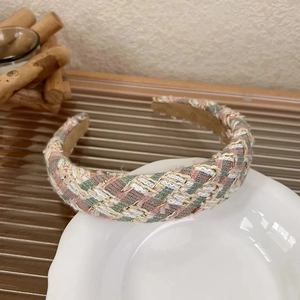 Close-up of pink tweed headband with gold weave texture on white ceramic dish