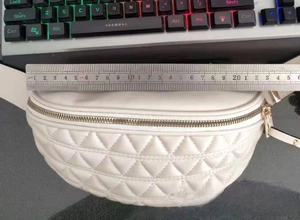 Gedetailleerde meting toont 20 cm breedte voor de witte gewatteerde crossbody heuptas