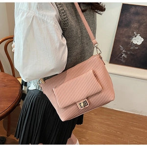 Detailed view of pink pleated shoulder bag with gold clasp shown in lifestyle setting