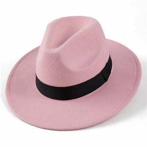 Detail view of pink wool fedora hat with black decorative ribbon on white background