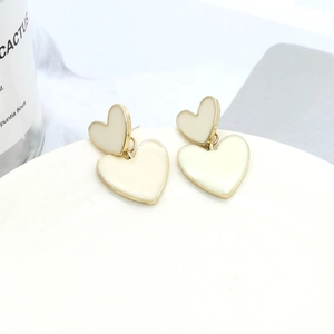 Detail of cream heart earrings with gold trim on a white plate, elegant style