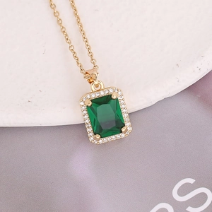 Macro shot of an emerald-cut green gemstone necklace with pavé zircon halo detail