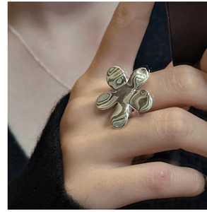 Gros plan d'une bague fleur en argent S925 poli portée au doigt avec finition brillante