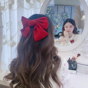 Detail shot of a large red bow hair clip worn by a model in a romantic indoor setting