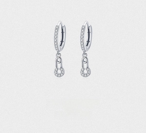 Macro detail of silver safety pin earrings with sparkling pavé cubic zirconia inlay