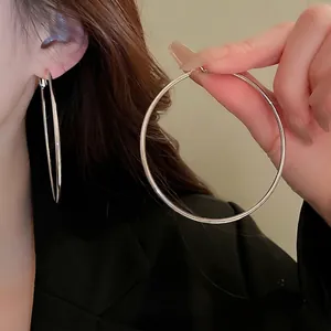 Minimalist large silver round hoop earrings for women shown worn on ear for scale