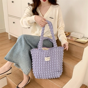 Detail of purple bubble texture tote bag with minimalist white brand label tag