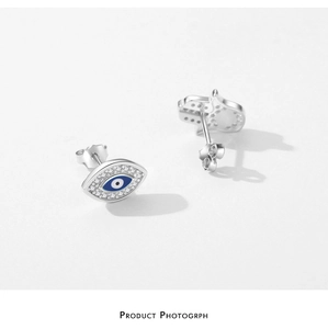 Vue macro de boucles d'oreilles asymétriques en argent s925 œil protecteur et main de fatma