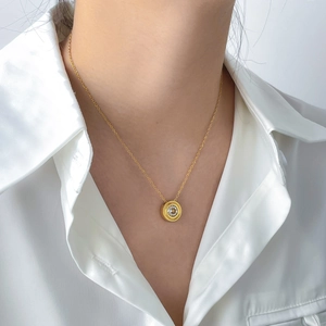 Detailed view of a gold double-layer chain necklace with a round zircon pendant on a model