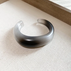 Detail of gradient acrylic cuff bangle with modern geometric design on linen texture