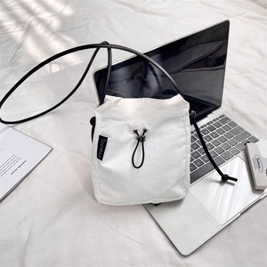 Dettaglio della borsa a tracolla in nylon bianco con coulisse nera ed etichetta del marchio