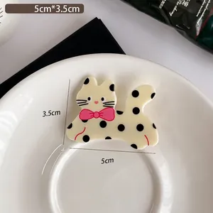 Polka dot cat hair clip in white acetate with a pink bow and 5cm x 3.5cm size