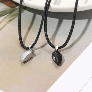 Detail of heart-shaped magnetic pendants in silver and matte black on woven cords