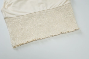 Detail of smocking technique on cream summer two-piece set showing elastic fabric texture