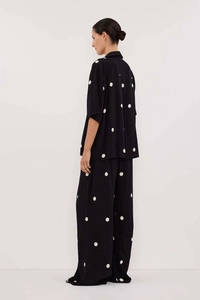 Side view of elegant black two-piece set featuring white polka dots and wide-leg trousers