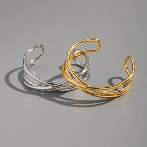 Detail of interlocking gold and silver geometric twist bangles on a dark background