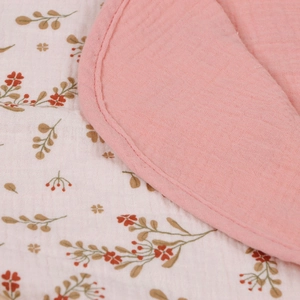 Detail of four-layer cotton muslin baby towel with floral print and pink reverse side