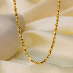 Detail of a golden twisted rope chain necklace resting on soft silk with a metallic finish