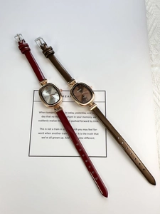 Close-up of vintage oval watches with burgundy and brown leather straps in detail