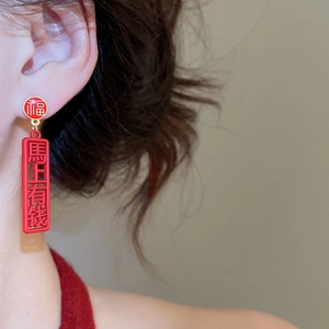 Detail of red Chinese style earrings with Fu and Ma Shang You Qian character charms