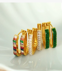Detail view of rectangular huggie earrings with colorful, white, and emerald stones